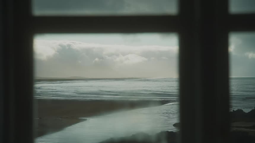 Outside the window is the beach from a remote cabin