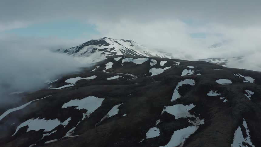 Aerial landscape of sun rising over snowy peaks covered by clouds
