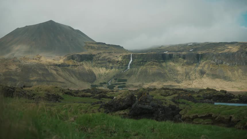 Majestic mountain with a waterfall flowing down and lowhanging clouds