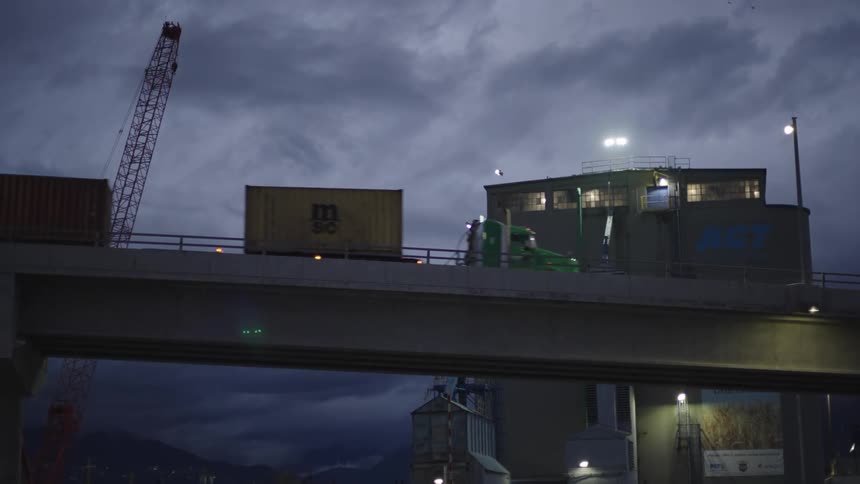 Truck drives in front of an industrial building at night