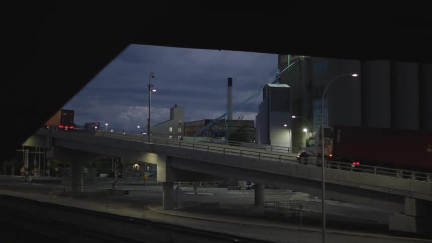 Truck drives in front of an industrial building with silos at night