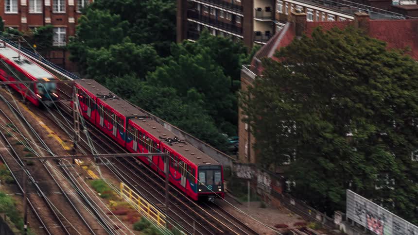 Public trains passing under a bridge with tracks amid a metropolis