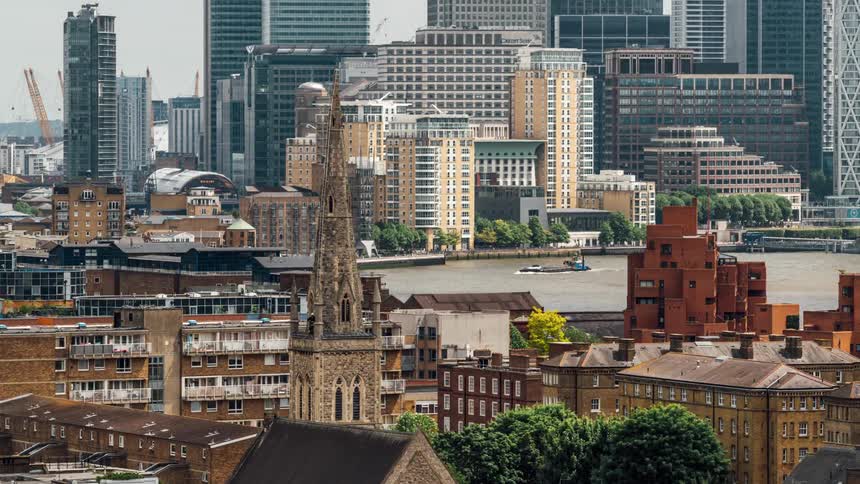 A river and an old tower in front of modern skyscrapers