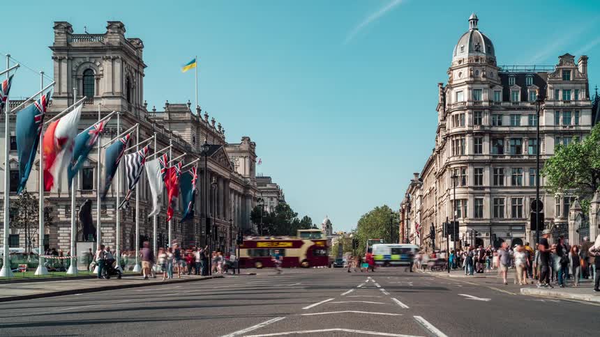 Timelaps of vehicle and pedestrian traffic in front of parliament square with british flags in front in london