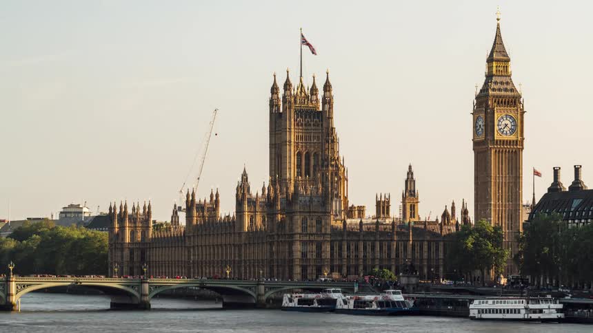 Traffic passing down and across the thames both pass big ben and the palace of westminster in london