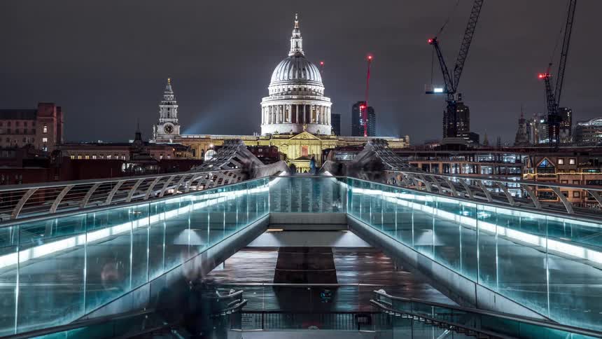 Tourists walk over the millennium bridge in london at night