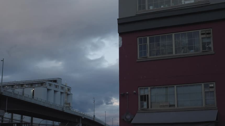 A building next to an overhead bridge with a vehicle going by