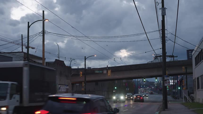 Traffic on the streets of a small city under a cloudy sky