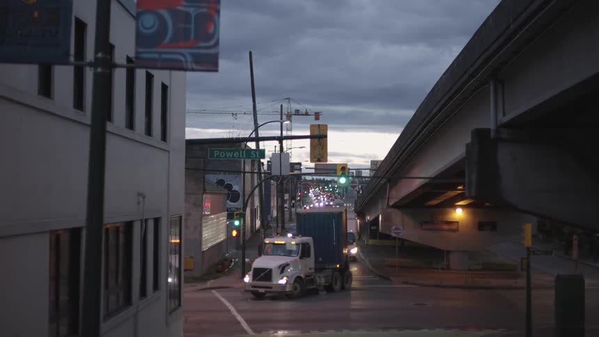 Traffic turns onto street passing under overpass on an overcast evening