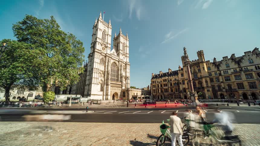 Cars vans and busses drive on highway in front of westminster abbey church in london