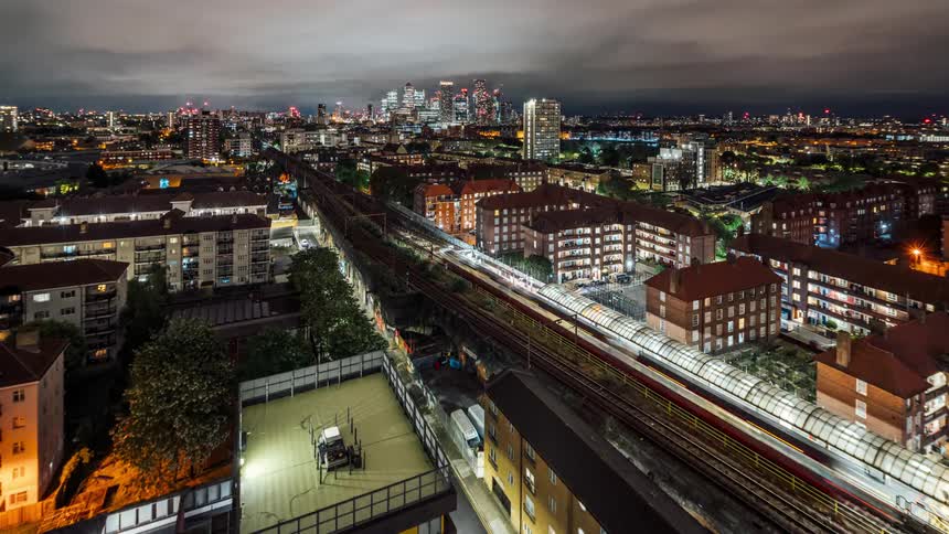 A train stops at a terminal in a bright city and then leaves