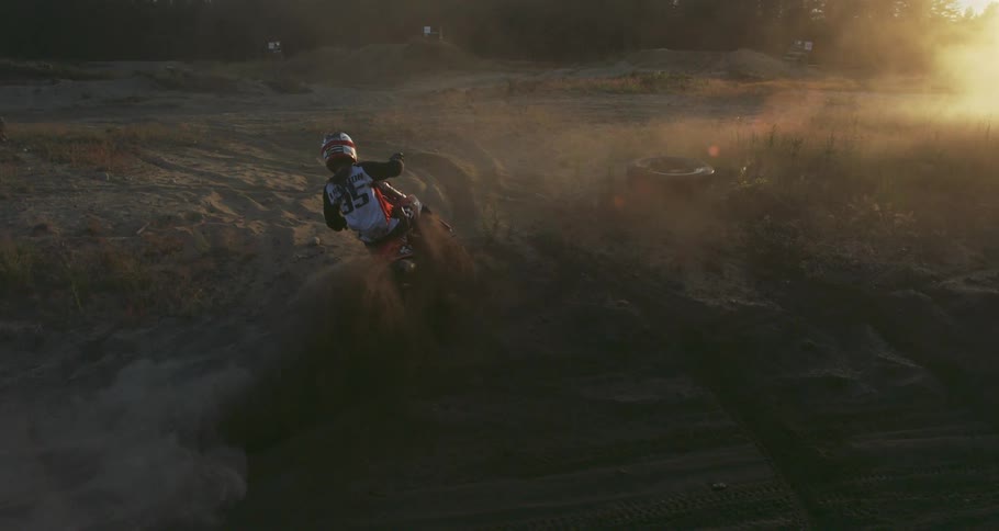 A person is doing motocross on a dirt track and is skidding and kicking up the dirt