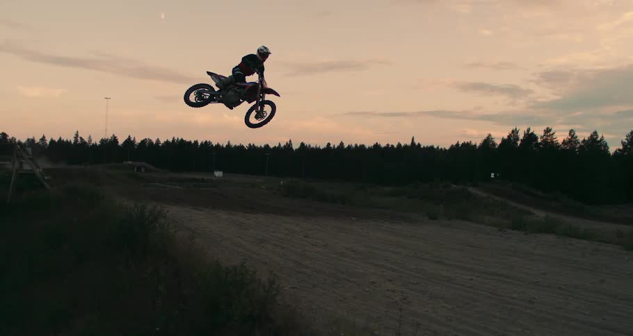 A man is in the air doing tricks on a motocross bike