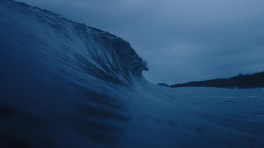 A powerful wave in the ocean under a cloudy sky