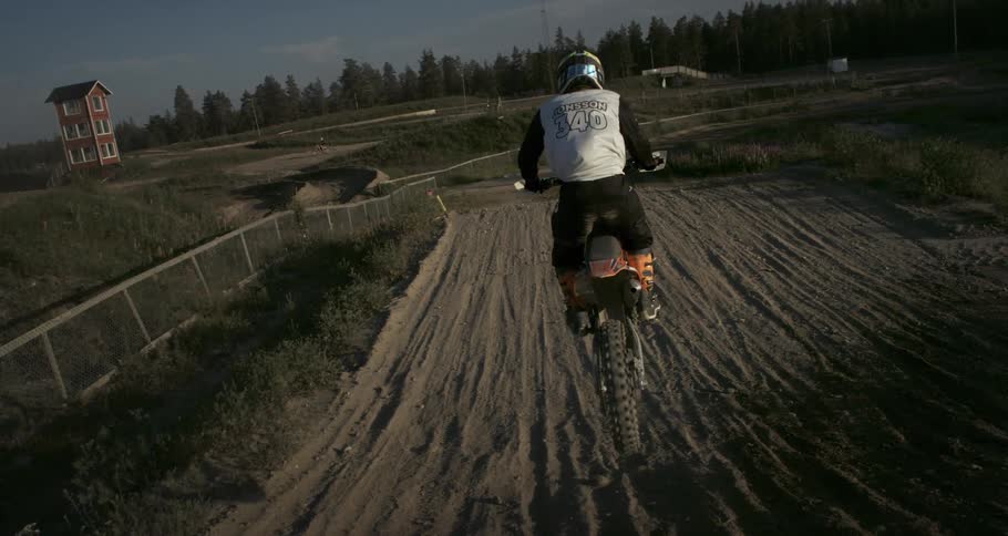 A person doing motocross is jumping over a dirt ramp
