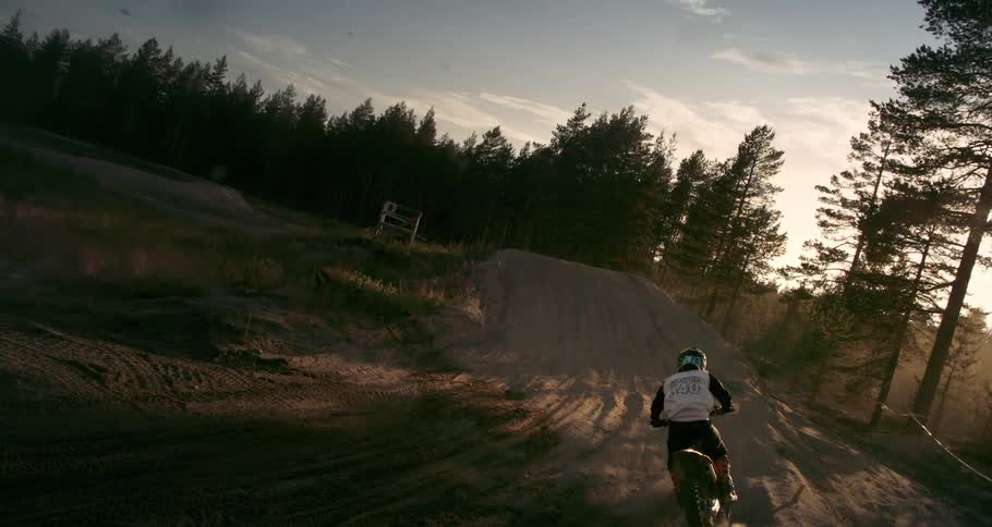 Slowmotion view of dirt flying with a person on a motocross track during late afternoon