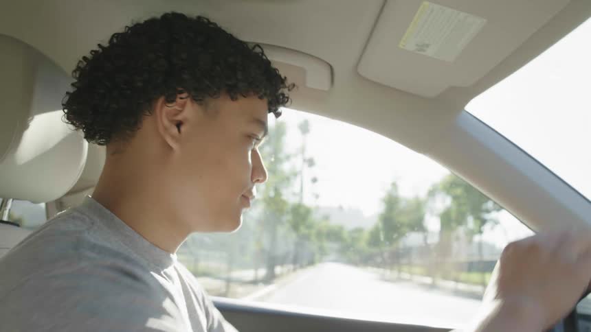 Closeup of the face of a young man driving a car