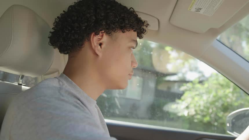A young man is in a car and driving