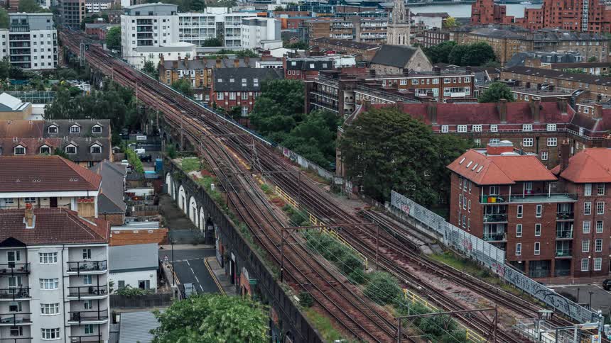 Trains pass on the tracks between apartment buildings on a windy day