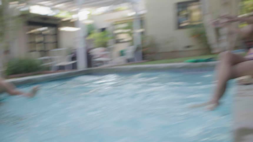 Woman outside the pool throwing water at a playfully man