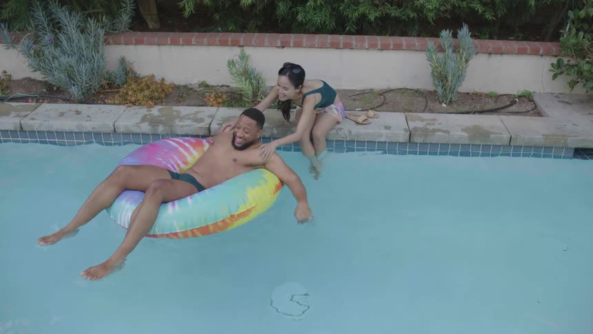 A man floats over to a woman in the pool