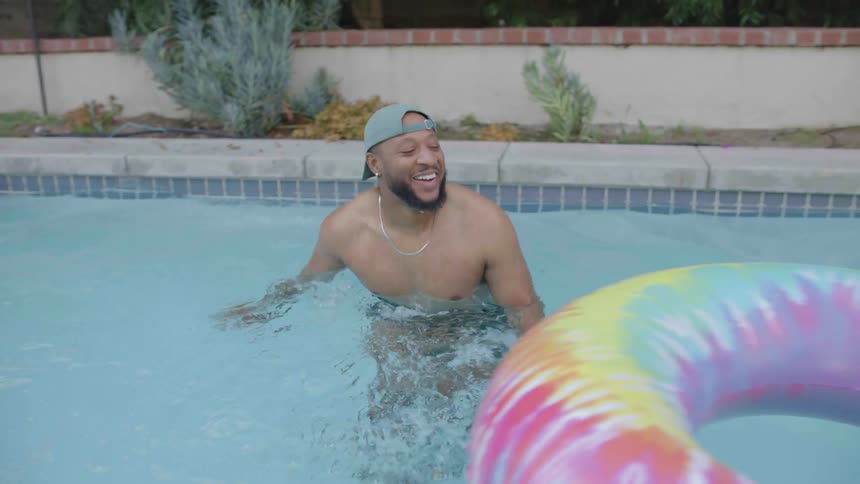 Man entering the pool taking off his cap and tossing it away