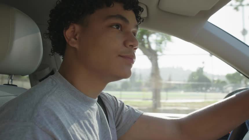 A boy driving a car in a calm neighborhood