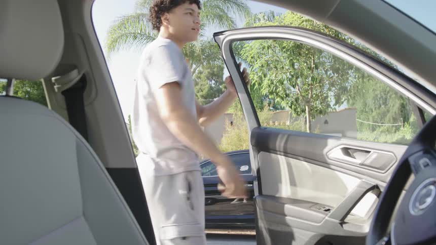 Young man getting out of the car and using his cellphone