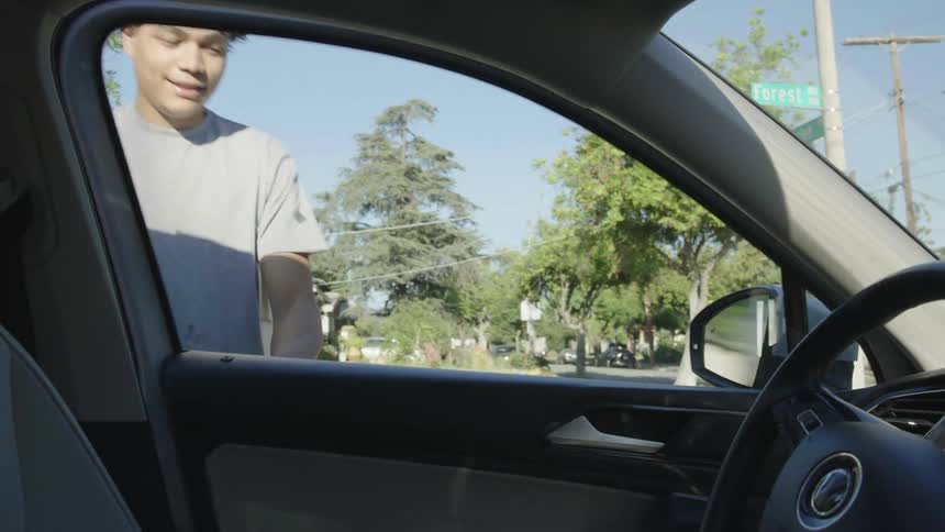 A teenager rushes to step into a cars drivers seat