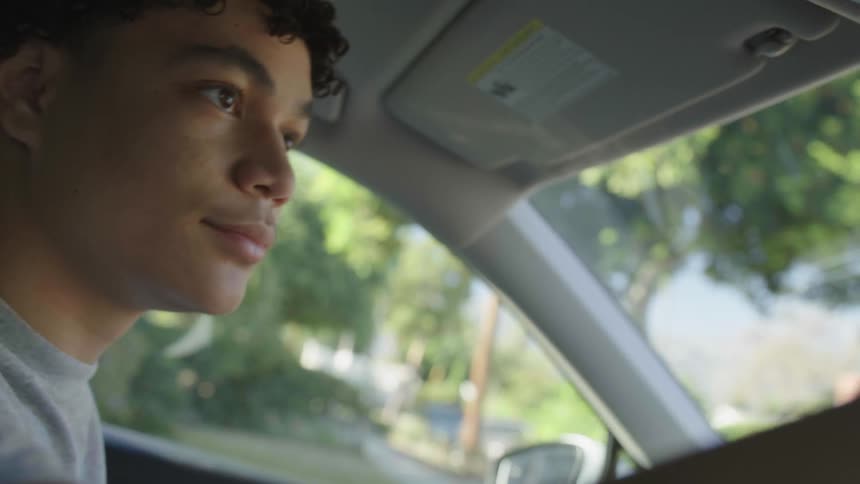 A young man in his car setting his mirror