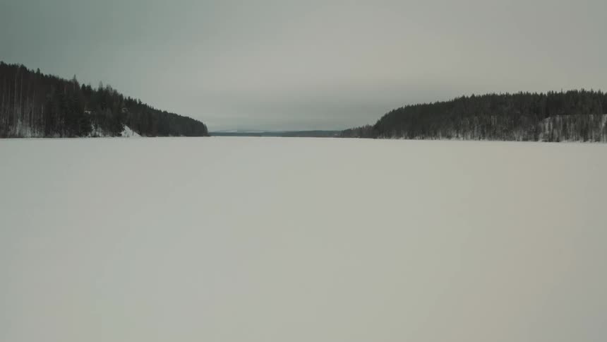 Panorama of a natural area with the ground covered in snow and forests around on a cloudy day