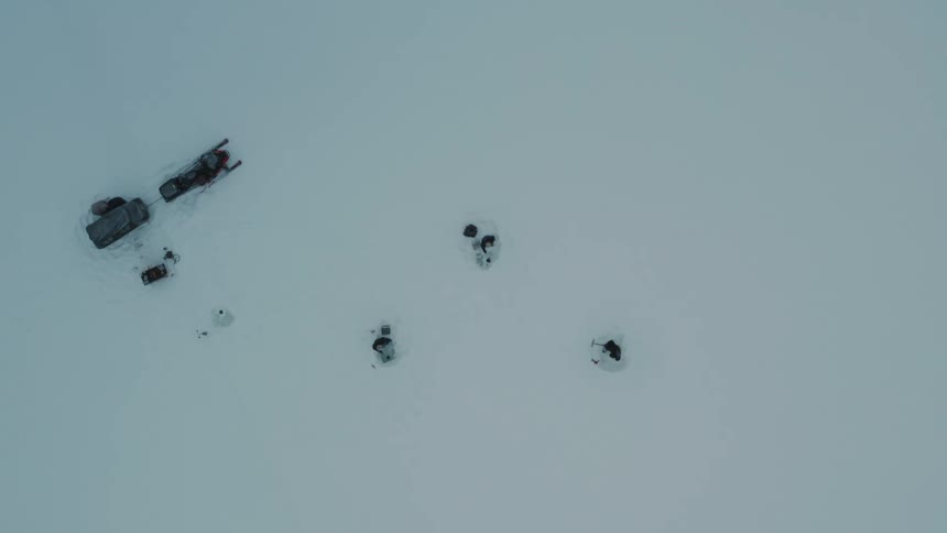 Three people in the heavy snow next to their snowmobile