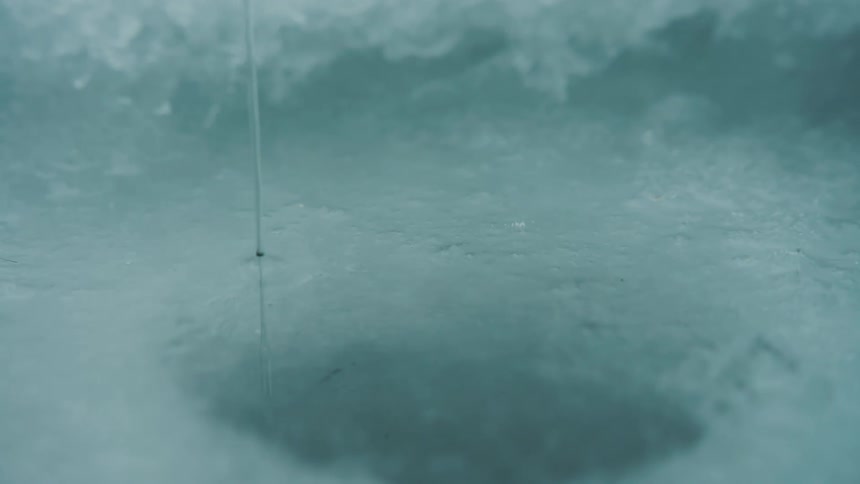 Frozen fishing line going through a hole in the ice