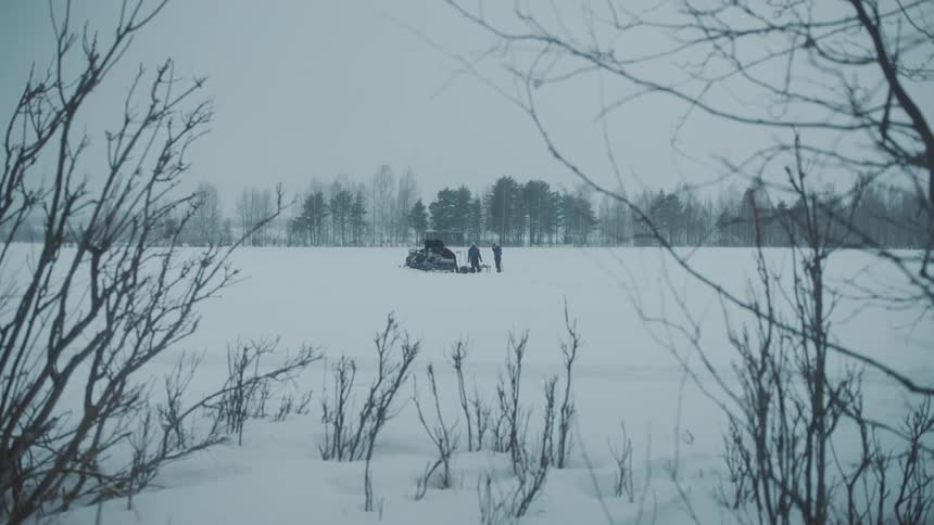 View of people in the snow surrounded by forests on a cloudy day