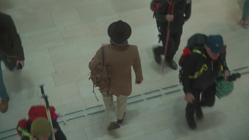 A person on a brown jacket walking in the midst of other people