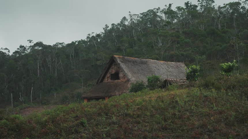 A wooden cabin in the mountains under a cloudy sky
