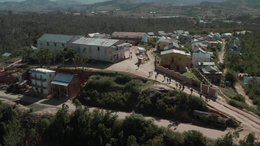 A small group of people walking along a dirt road in a small rural town