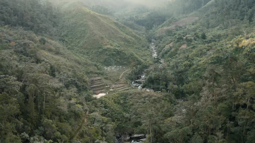 Aerial panorama of a natural environment under the mountains with a small river flowing in the daylight