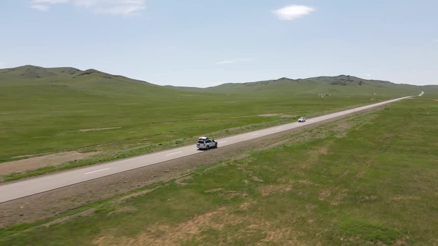 Aerial view of car driving on a country road in the green field