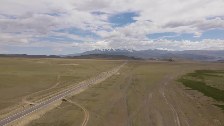 Aerial of a car driving on country road in the field