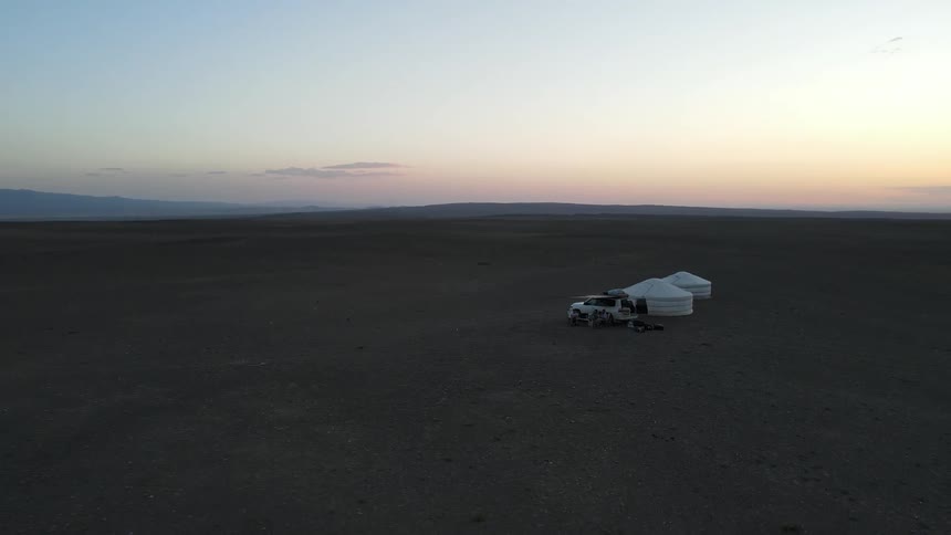 A camper in the desert with a tent setup near a car
