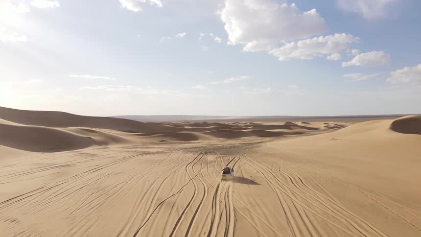Aerial of a car driving through the desert on a hot day