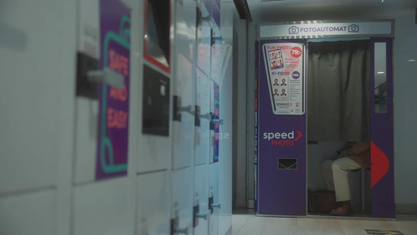 A man sitting in a photo booth waiting for his photos to be taken