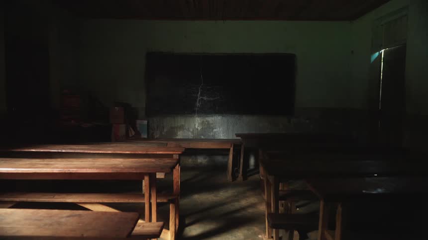 An old historical classroom with large wooden desks and a blackboard