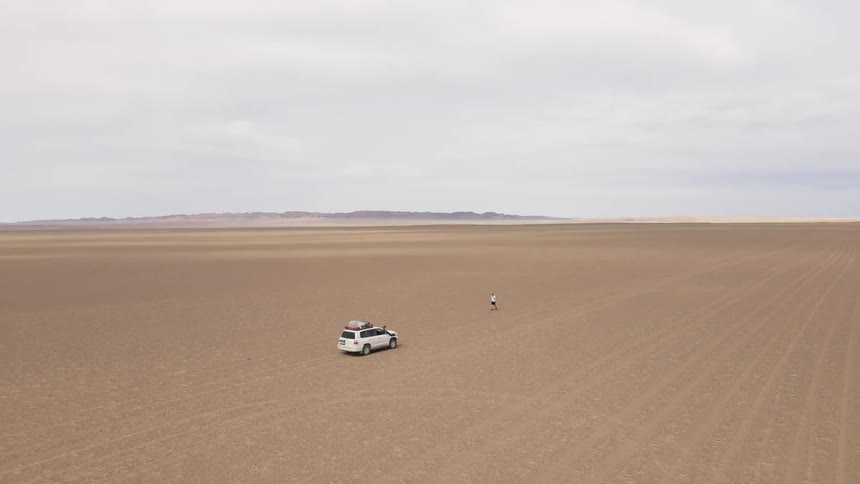 A person is walking towards his car in the desert