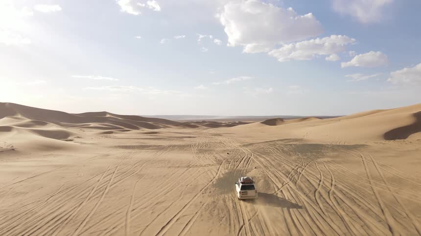 Aerial view of a white jeep driving in the desert
