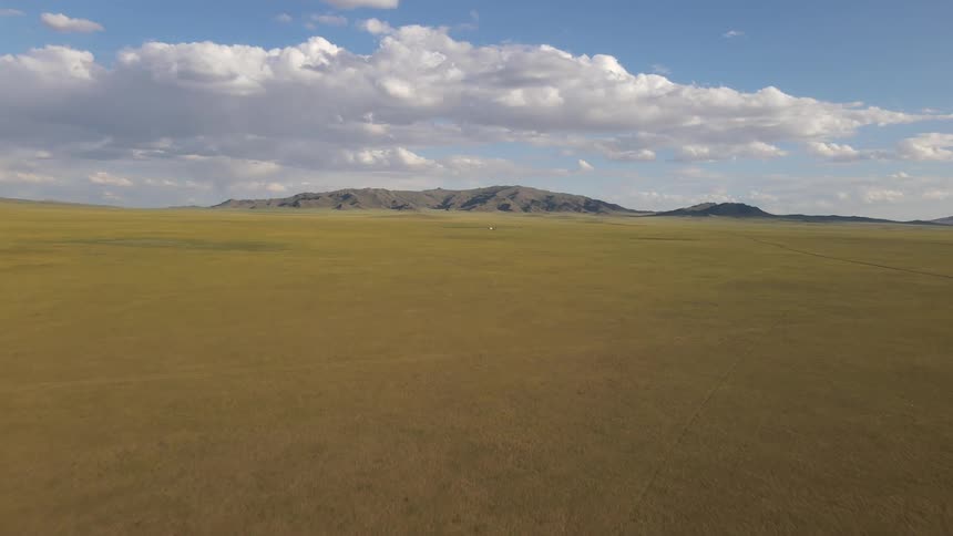 Panorama of a grassland with a mountain range on the horizon on a cloudy day