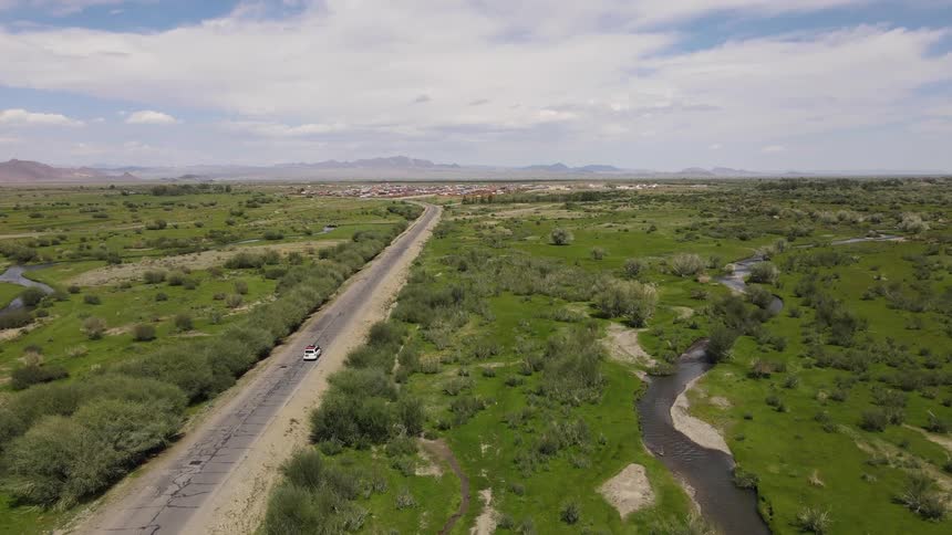 Vehicle drives along highway between rivers on route to town and foggy mountains