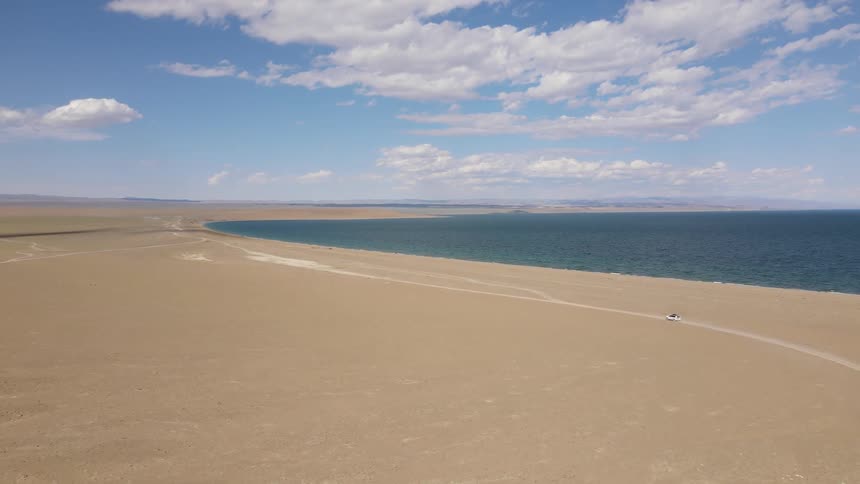 Aerial view of a car driving next to the ocean