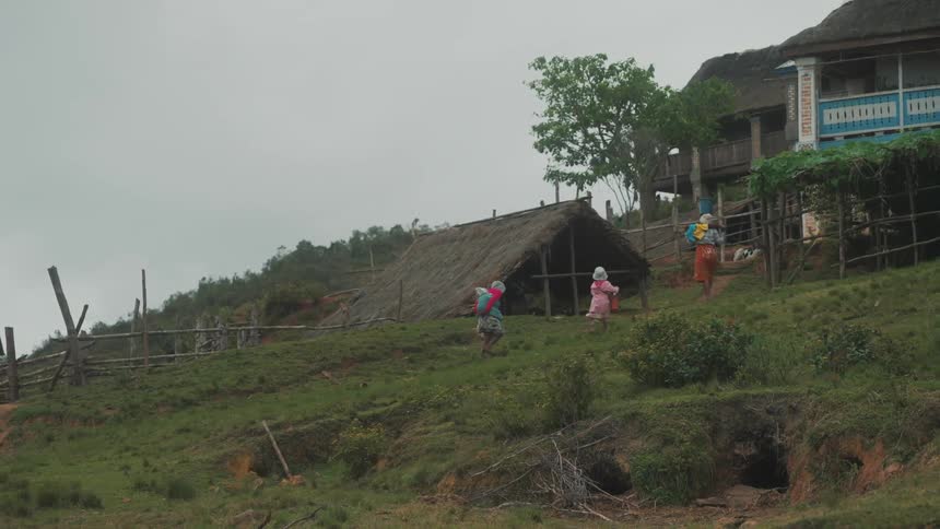 A woman and two children walk up a hill to a vintage looking house